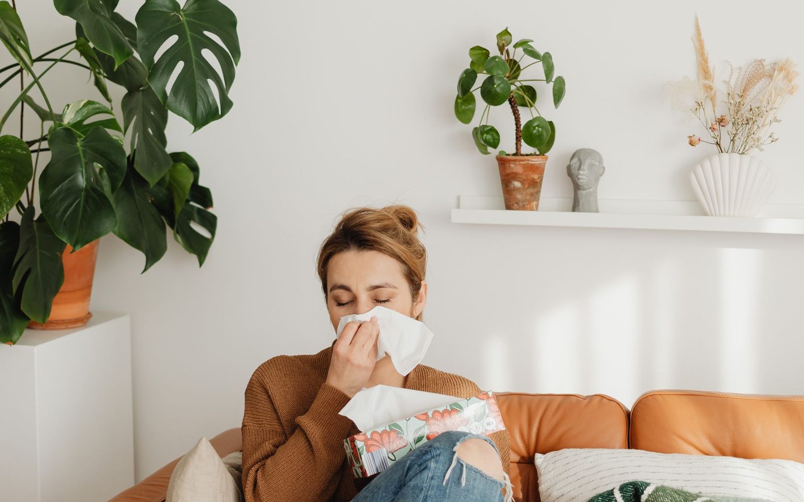 Người phụ nữ ngồi trên ghế dùng khăn giấy lau mũi do viêm mũi dị ứng